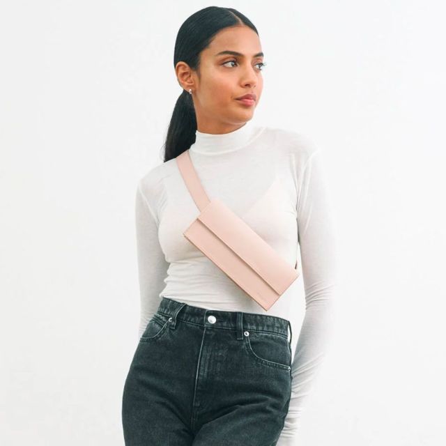 woman in white top and black jeans wearing a light pink crossbody bag