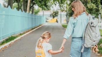 a mom walking holding her daughter's hand for a story on tics in kids