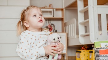 toddler girl playing with doll in her room at nap time