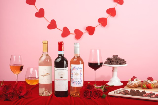three bottles of wine on a table decorated for valentine's day