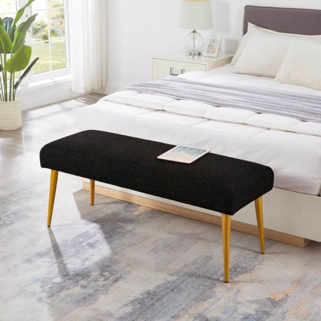 black upholstered bench at end of a bed