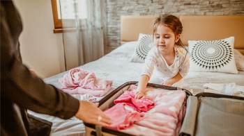 a little girl in a hotel room with her mom unpacking