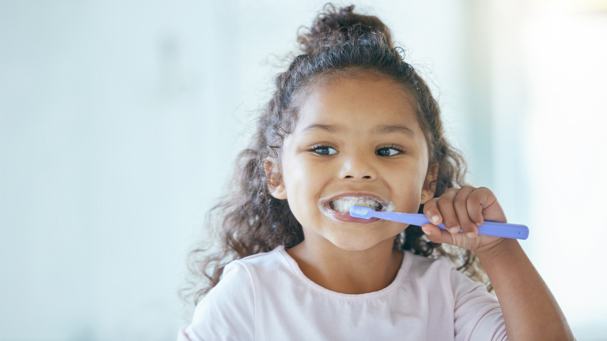 a kid learning how to be self sufficient by brushing her teeth alone