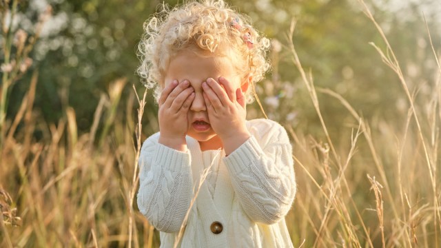 a little girl covering her eyes because she's suffering from pink eye in toddlers