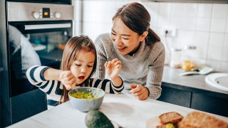mom and daughter making guacamole, showing how to get kids to eat veggies by involving them in cooking
