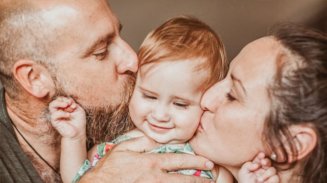 parents kissing their toddler on both cheeks, which is one of the best family photo ideas with toddlers