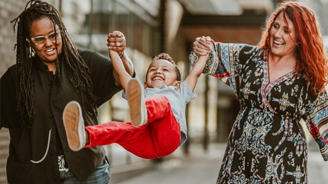 moms swinging their toddler in the air, which is one of the best family photo ideas with toddlers