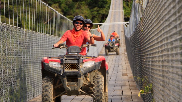 a couple giving the thumbs up while driving an atv over jorullo bridge, one of the most fun things to do in puerto vallarta