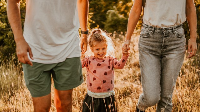 a mother and father walking hand in hand with their toddler, which is one of the best family photo ideas with toddlers