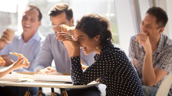 a picture of a woman laughing with co-workers over would you rather questions for adults