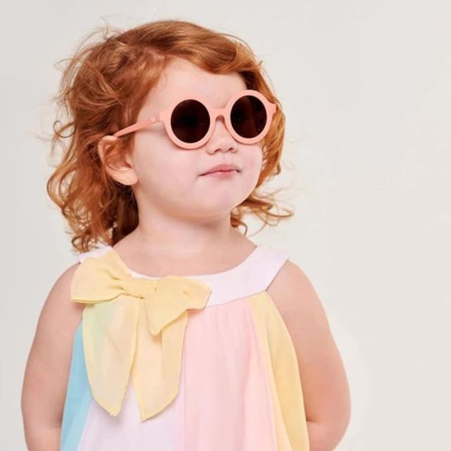 redheaded little girl wearing round toddler sunglasses