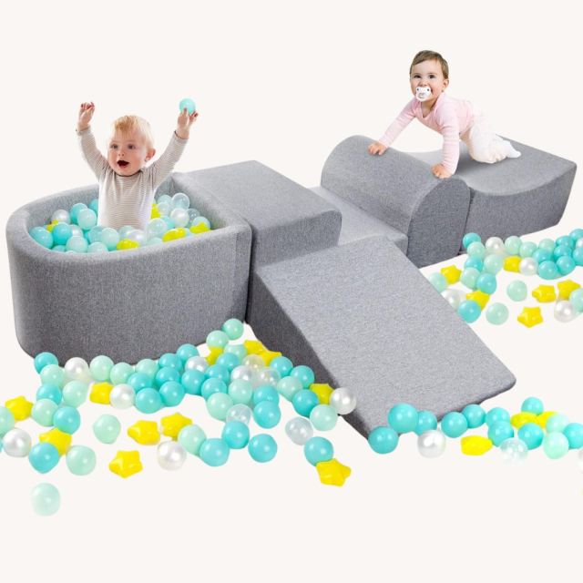 two toddlers playing in at-home ball pit and climbing toy