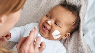 a mom putting cream on her baby to help with a baby skin concern