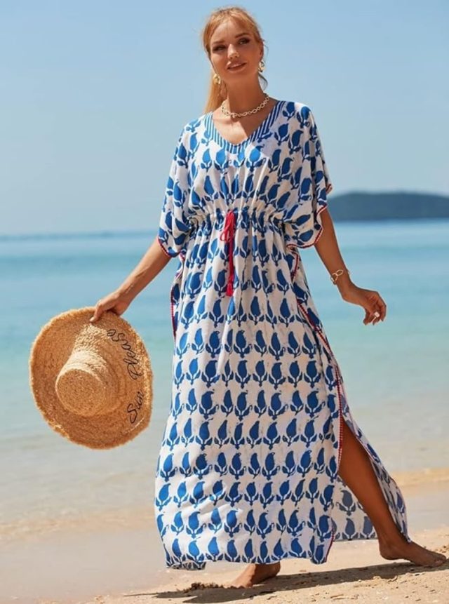 woman standing in cantan on the beach holding a hat