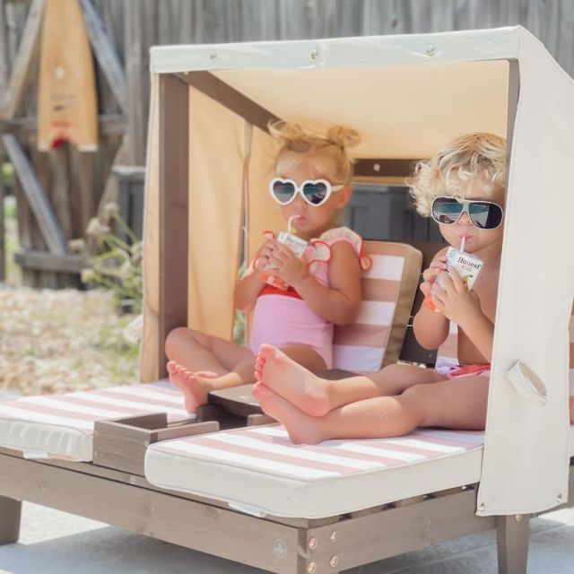 two kids on child size chaise lounges with canopy