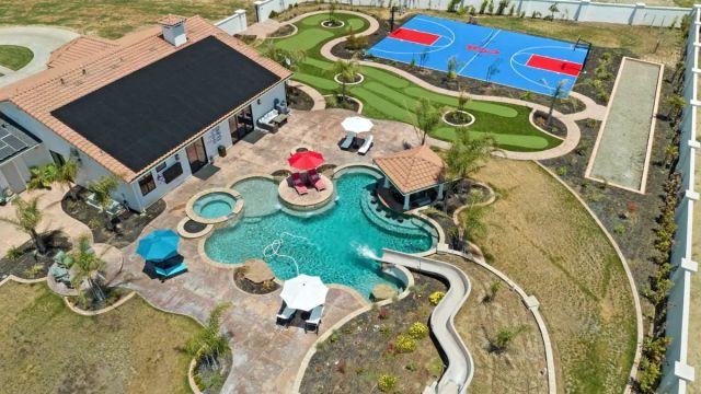 aerial view of huge backyard with pool, putting green, and basketball course