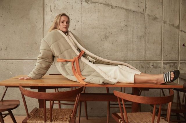 woman wearing homecoat sitting on top of a dining table