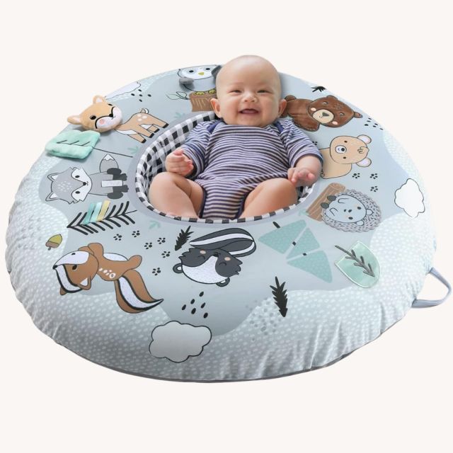 baby laying in the middle of a donut style play cushion