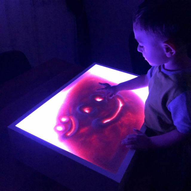 child playing with a purple light table