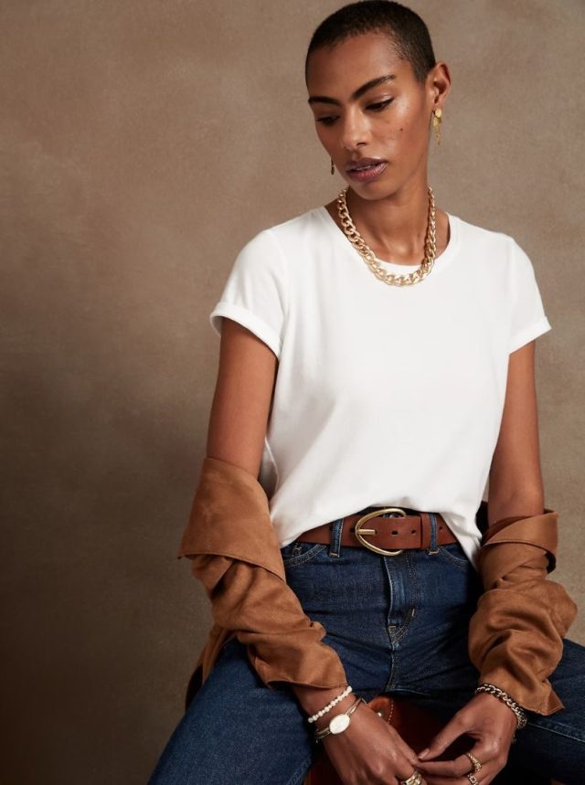 woman wearing white crewneck t-shirt, dark jeans, and gold jewelry