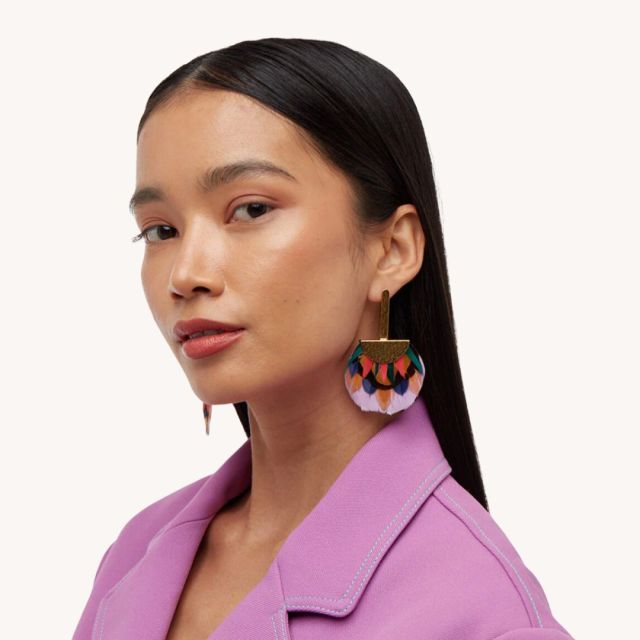 woman wearing lilac blazer and colorful feather statement earrings