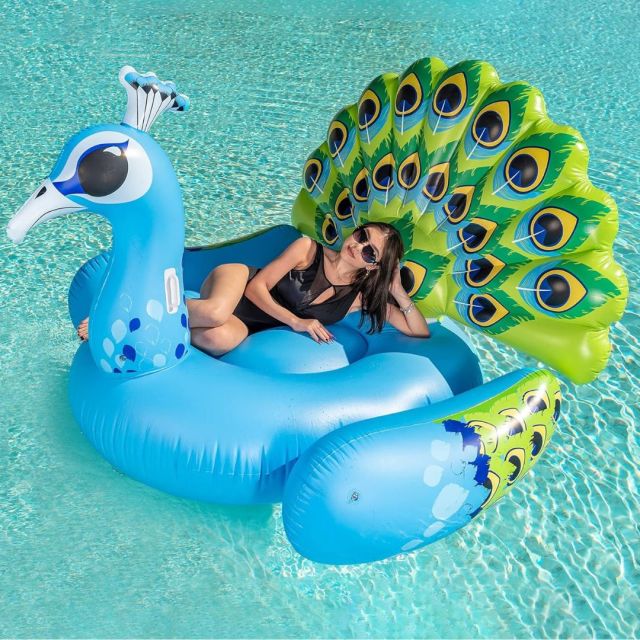 woman reclining on peacock shaped pool float in pool.