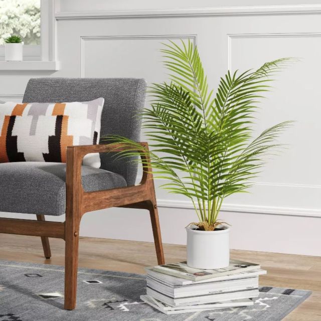 faux palm on stack of books by easy chair