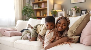 a mom lying on the couch with her toddler playing a game to play while lying down