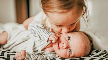 a toddler kissing her baby brother or sister who has one of our uncommon baby names