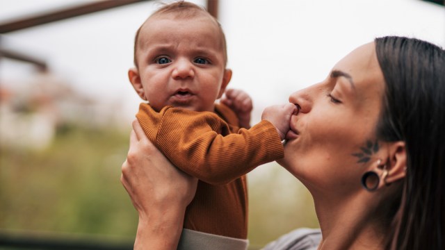 a mom kissing her baby's hand for a story on sensory development