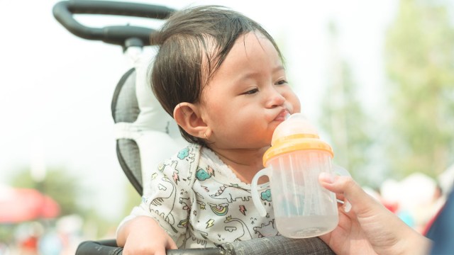 a baby sipping water through a cup with straw