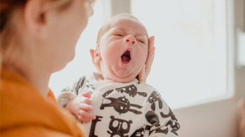 Tired infant yawning because he's having baby sleep problems