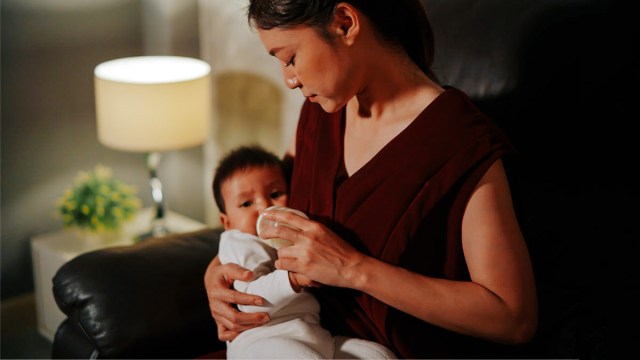 A mom feeding her baby in the night wondering when it will be time for night weaning