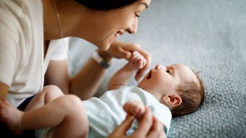 A baby clutching mom's hand and looking into her eyes, part of their sensory development