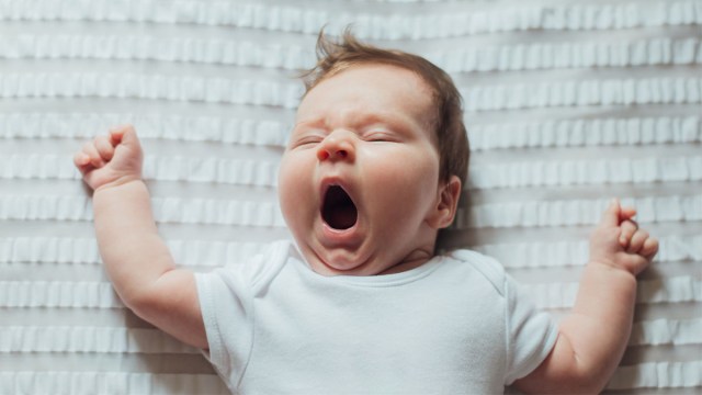 a yawning baby who is learning to sleep thanks to tips from newborn care specialists