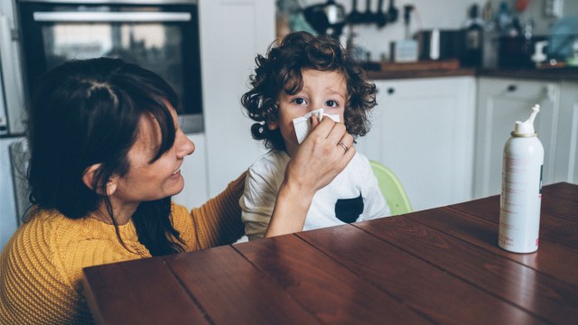 a mom using saline spray on her sick toddler, one of the best cold and flu medicine for kids