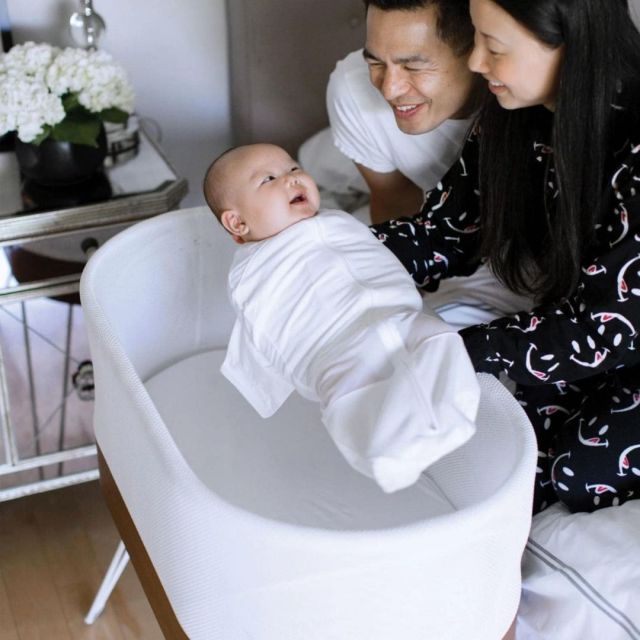 parents holding baby over snoo bassinet