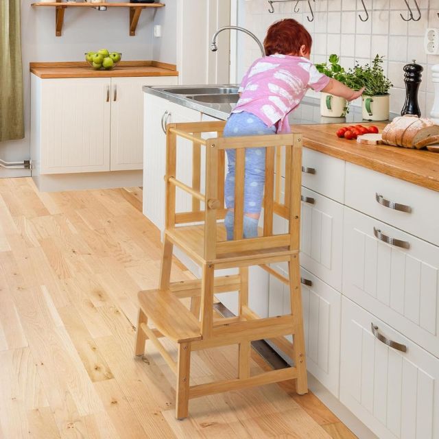 toddler standing on step stool in kitchen