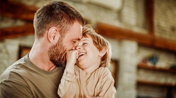 a little boy snuggling his dad for a story on parenting one-liners