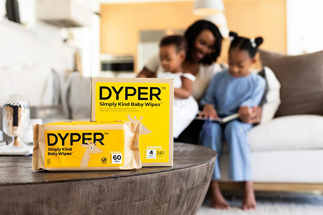 A family in the background of a box of DYPER diapers and a box of DYPER wipes