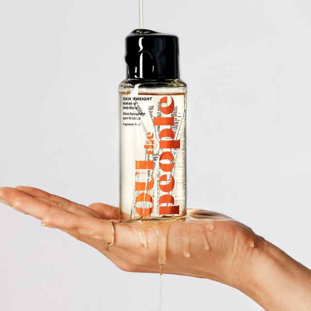 hand holding bottle of body oil from oui to the people