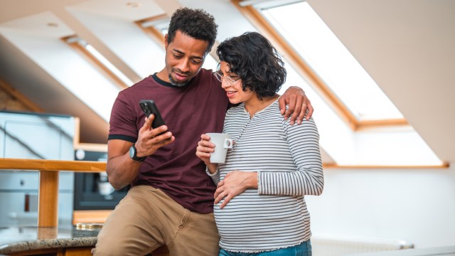 A pregnant couple looking at a phone and discussing digital nesting