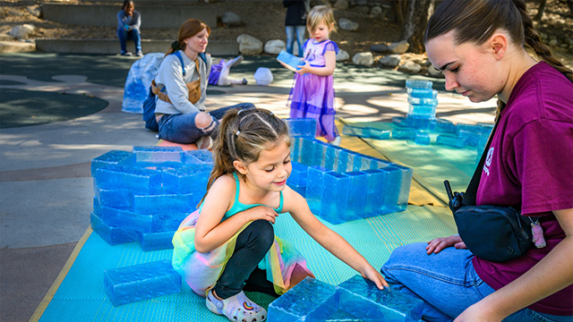 A little girl and her mom building out of pretend ice blocks at kidspace's winter frolic in LA