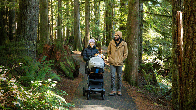 a couple on a walk through a forest pushing their stroller in oregon mt hood territory