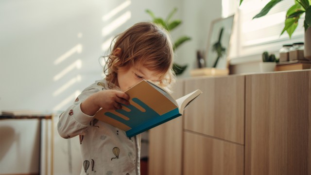 a toddler reading a book in their jammies