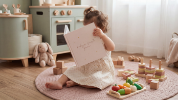 a toddler looking at a baby photo book from her first year, made using our first year photo book ideas