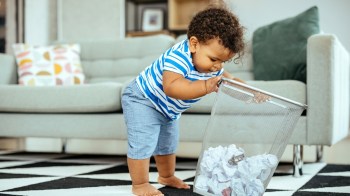 quirky toddler behavior from a little boy digging in the trash