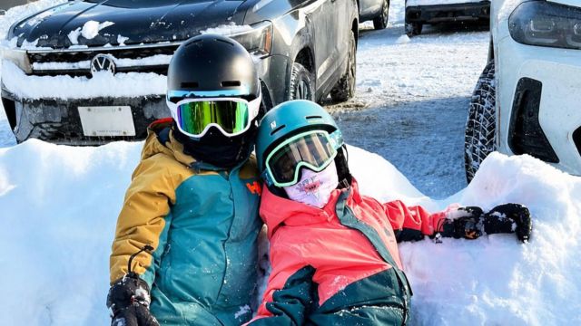 Siblings in ski gear leaning on a snow hill for an essay on things my kids do that I don't want to forget